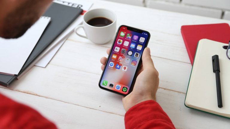 man holding smartphone displaying app icons