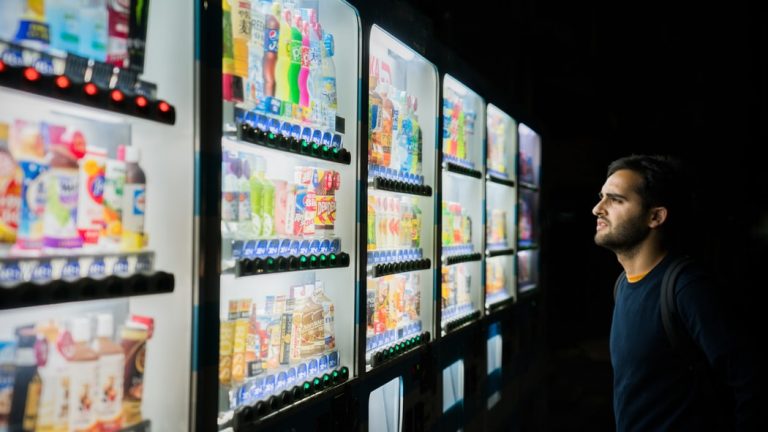 man looking at lines of vending machines