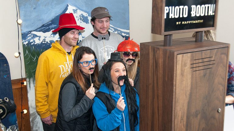 people posing at a photo booth with mountain thenme